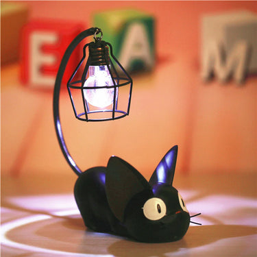 KittyNook Cat Co.’s Cute Black Cat Night Light holds a glowing bulb on its tail, with colorful blocks in the background.